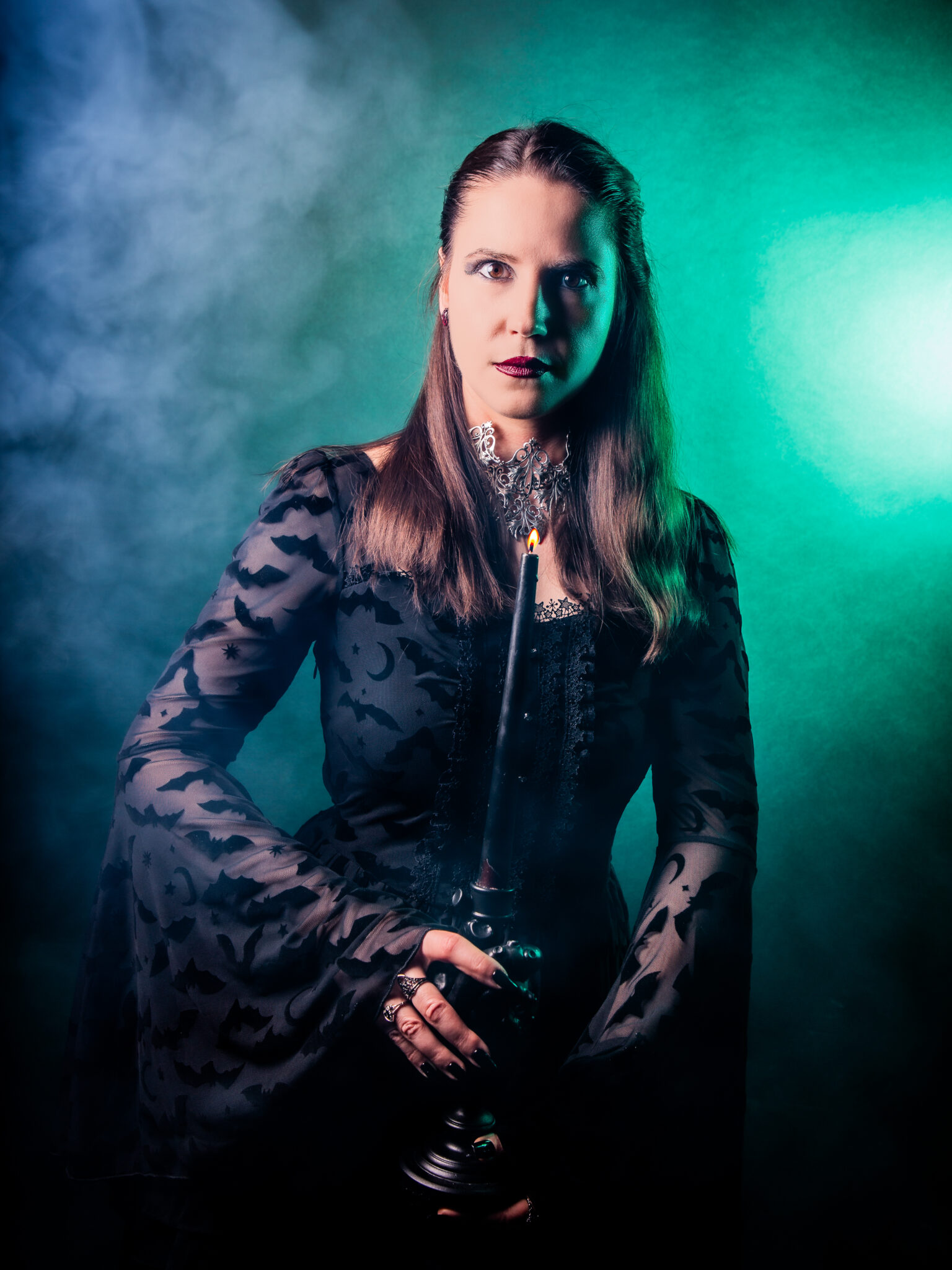 Inszeniertes Portrait einer Frau mit Kerze und intensiver Lichtführung in Grün und Blau, konzeptionelle Fotografie mit Nebel und Tiefe, erstellt von einer Fotografin in Bremen